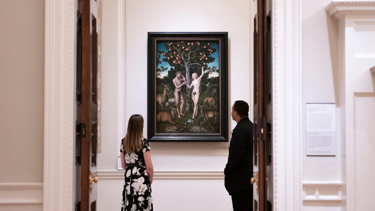 People looking at a painting of Adam and Eve in the Garden