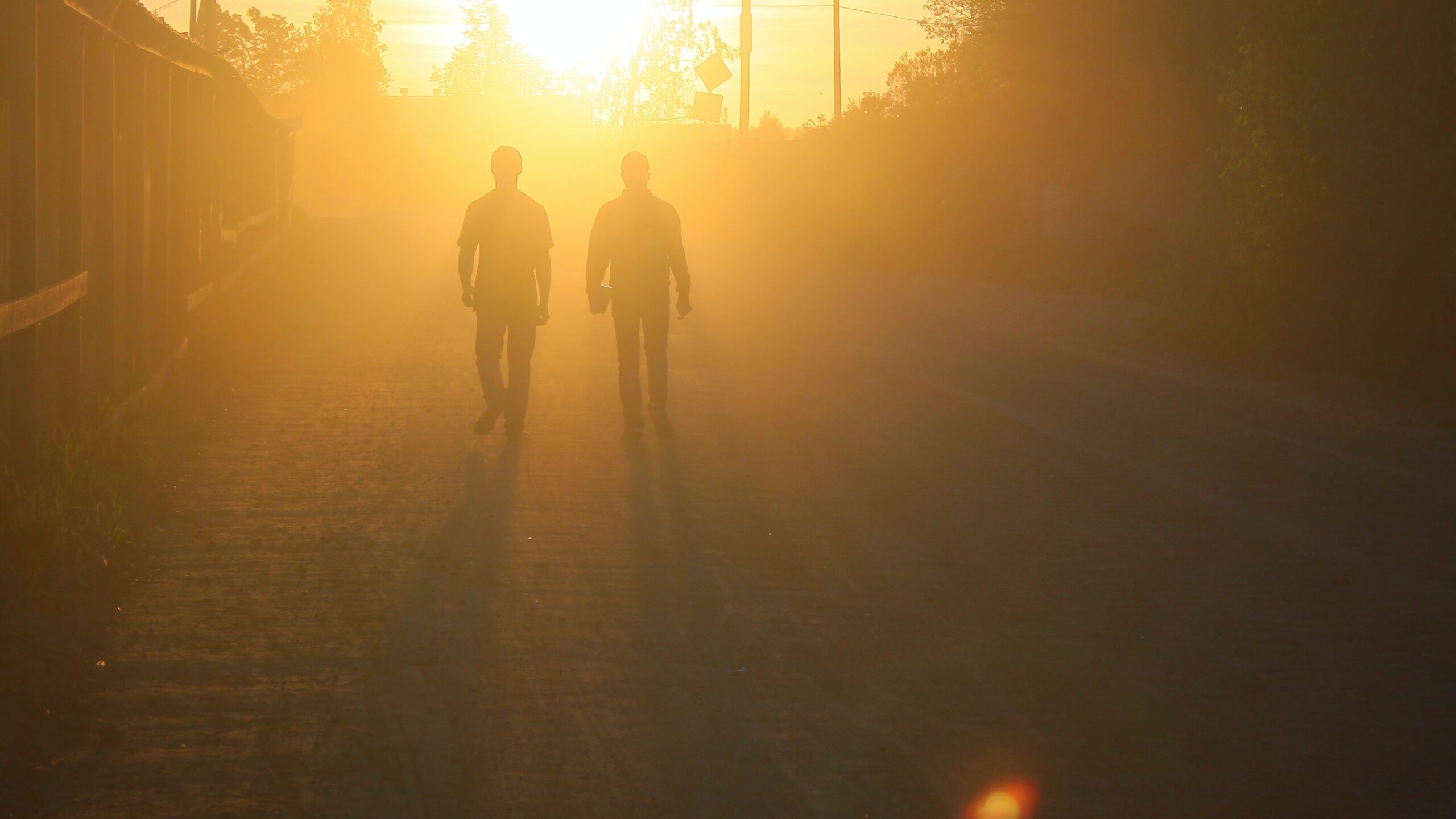 Two silhouettes walking toward the sunset