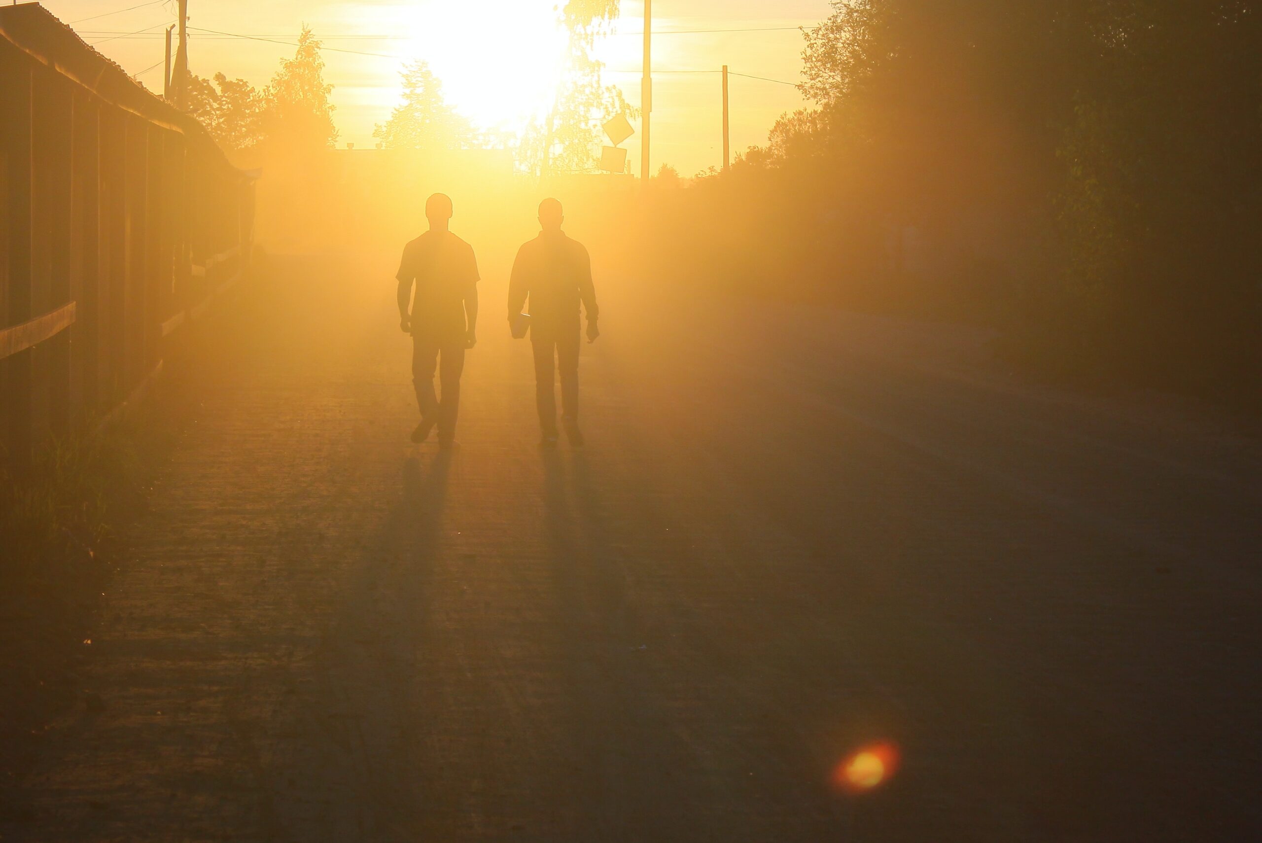 Two silhouettes walking toward the sunset
