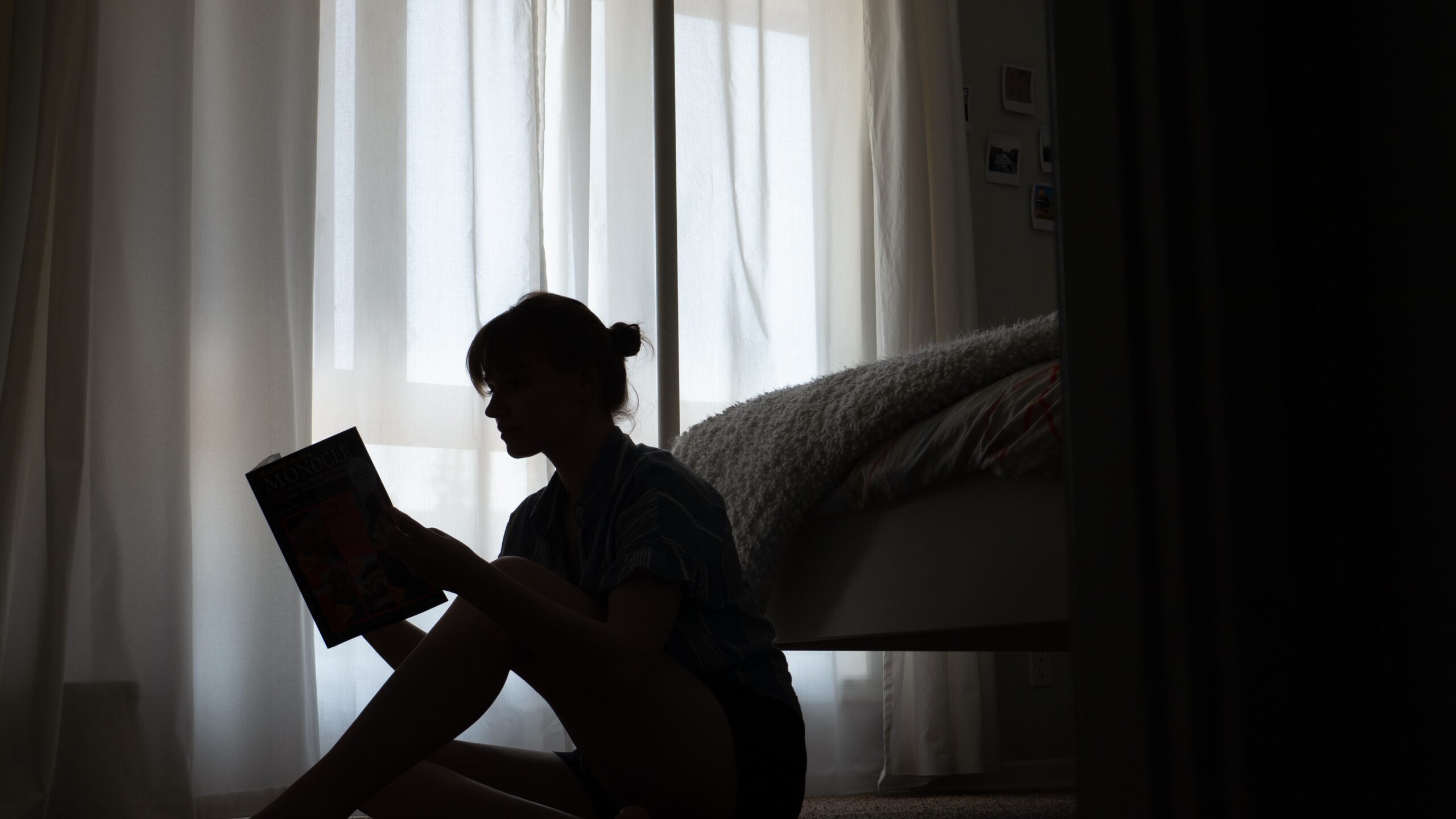 silhouette of woman reading book on floor