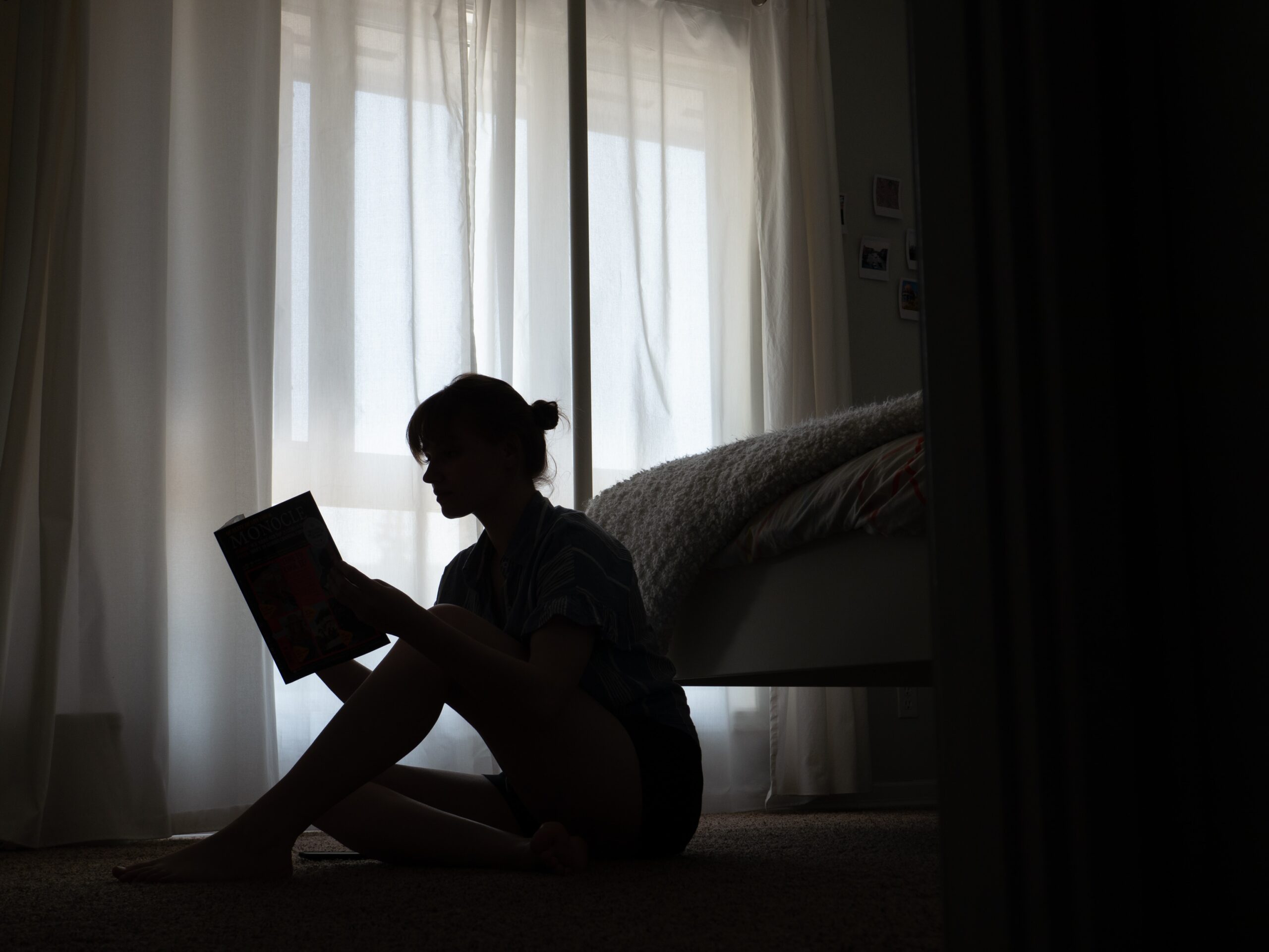 silhouette of woman reading book on floor