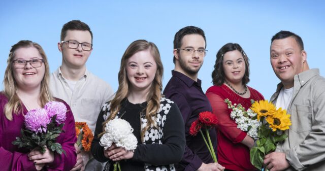 six individuals with Down syndrome holding flowers