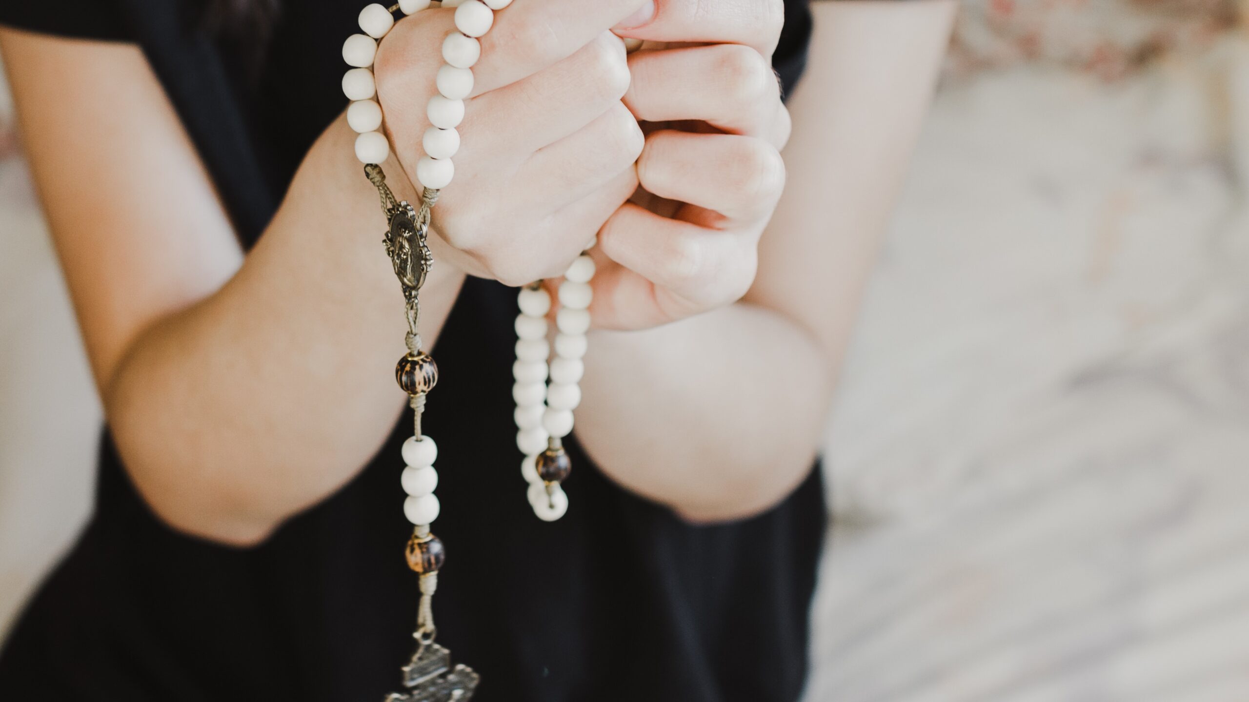 woman's hands holding rosary