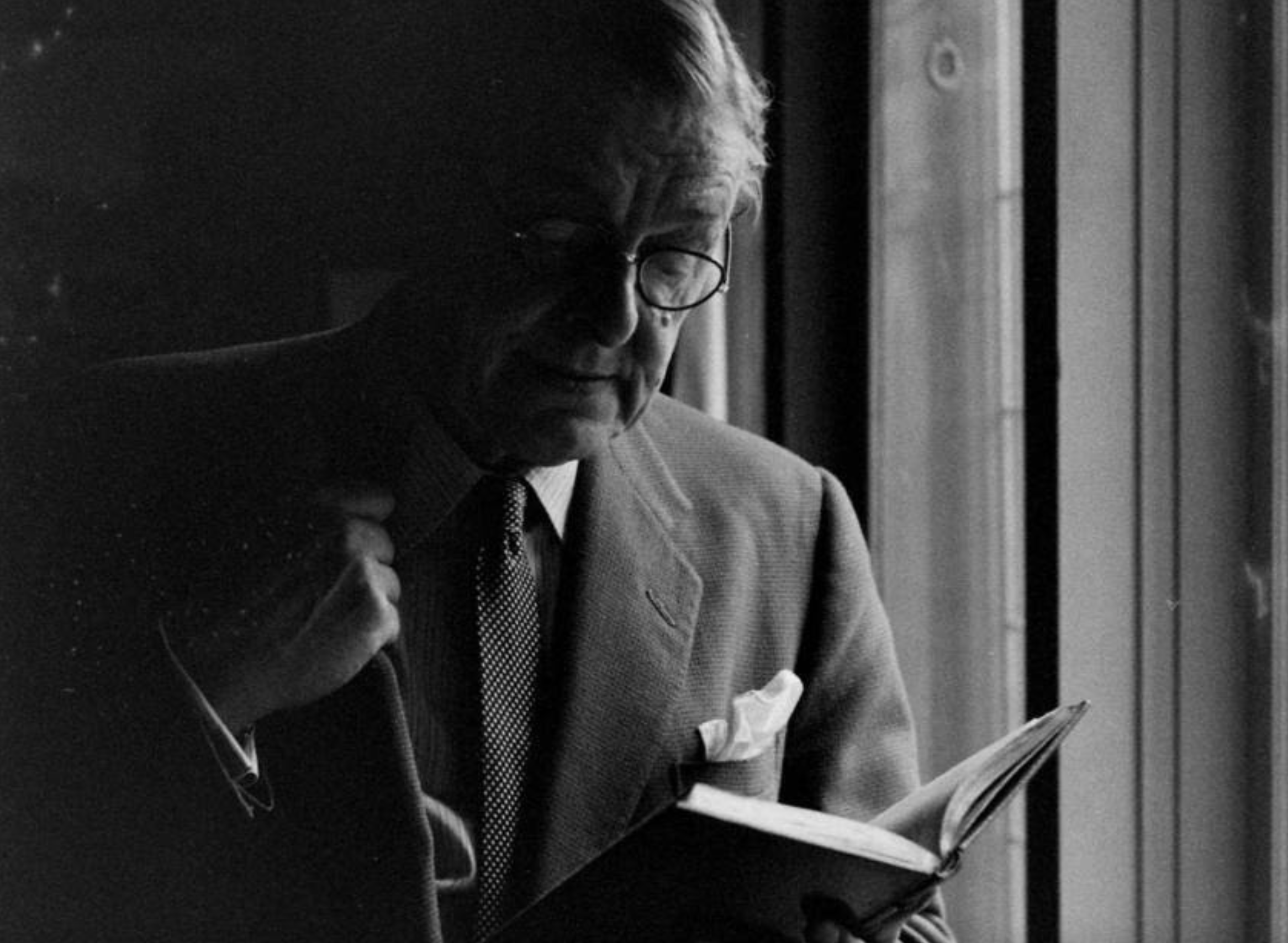 portrait of old white man reading book near window