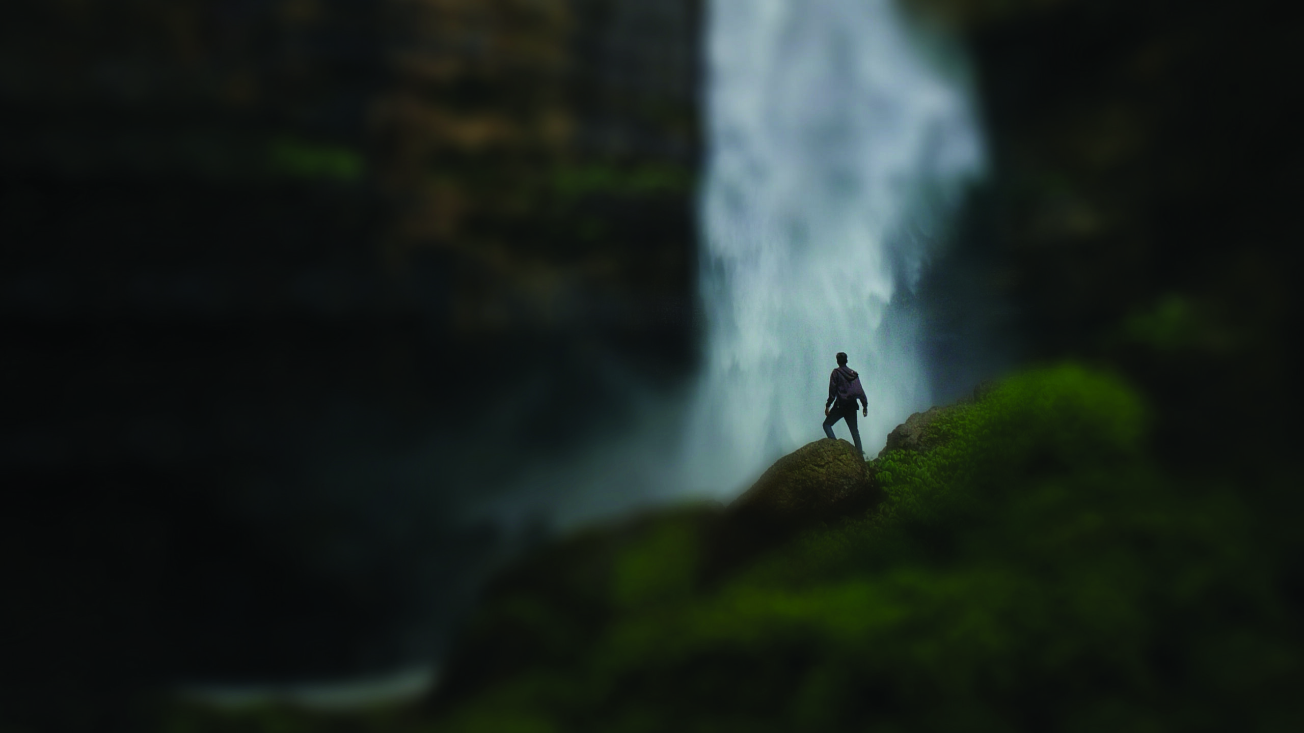 person standing in front of waterfall at night