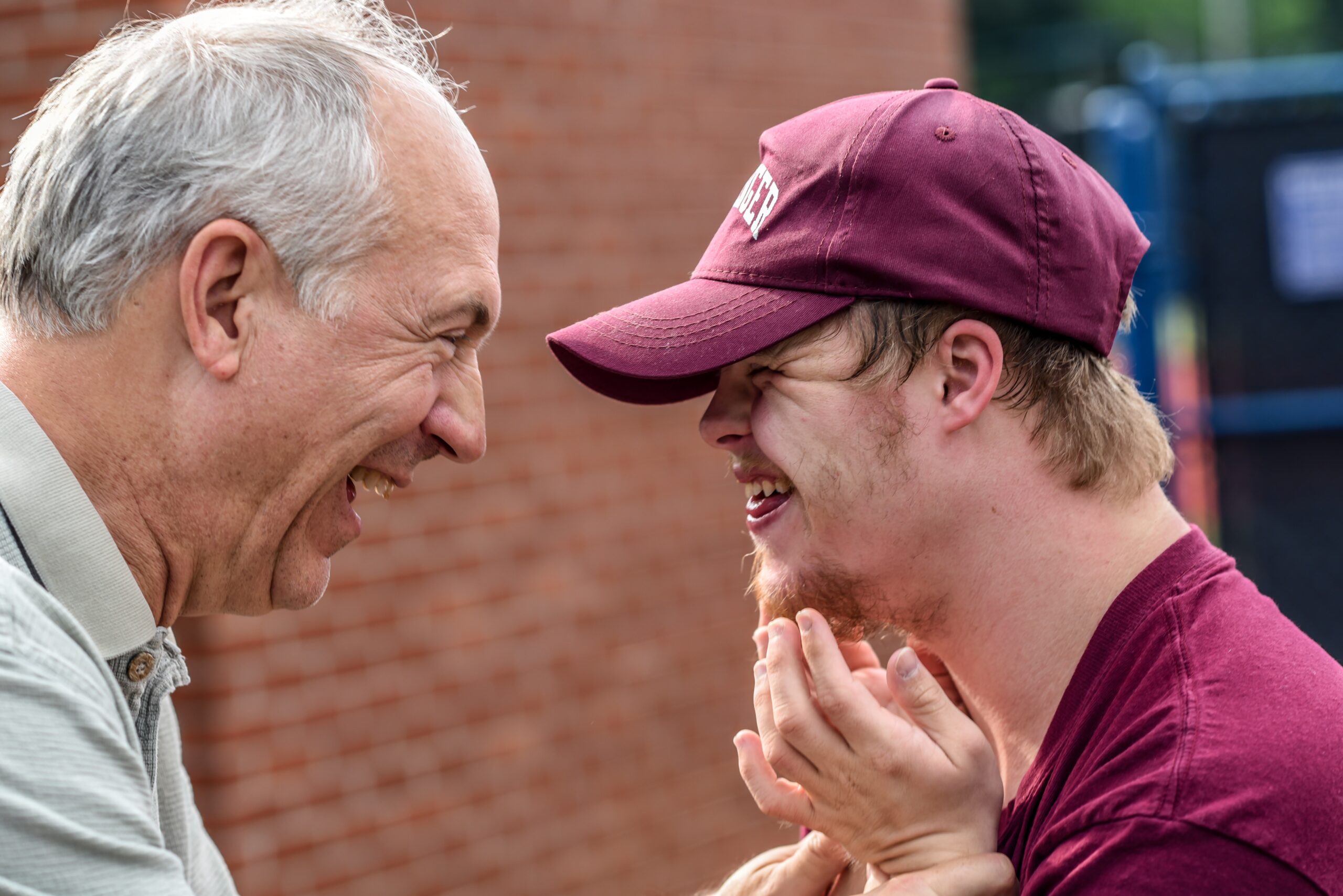 son and father smiling brick wall in background
