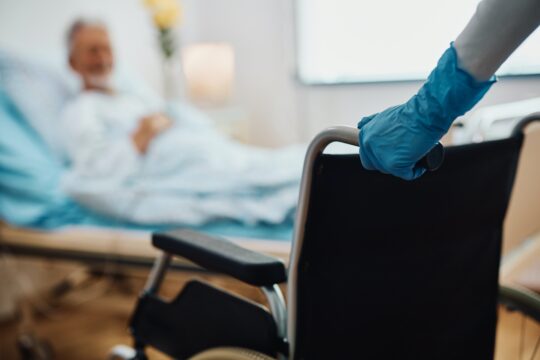 physician holding a wheelchair for a dying patient