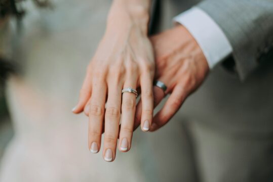 Man and wife holding out hands with their wedding bands