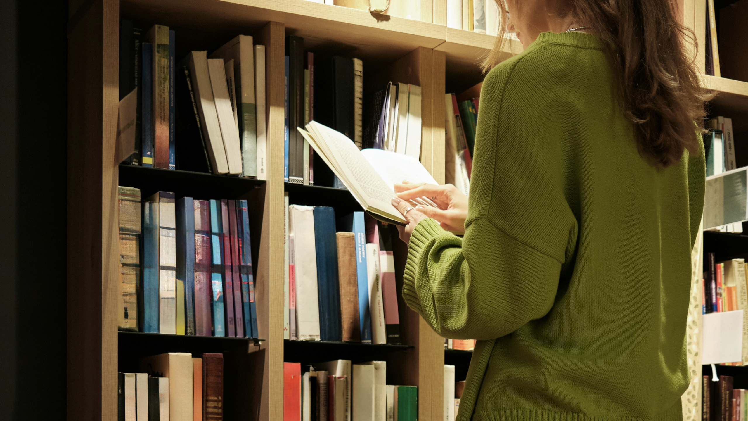 person reading in front of a shelf of books