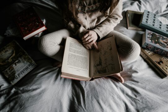 A child reading a book in bed