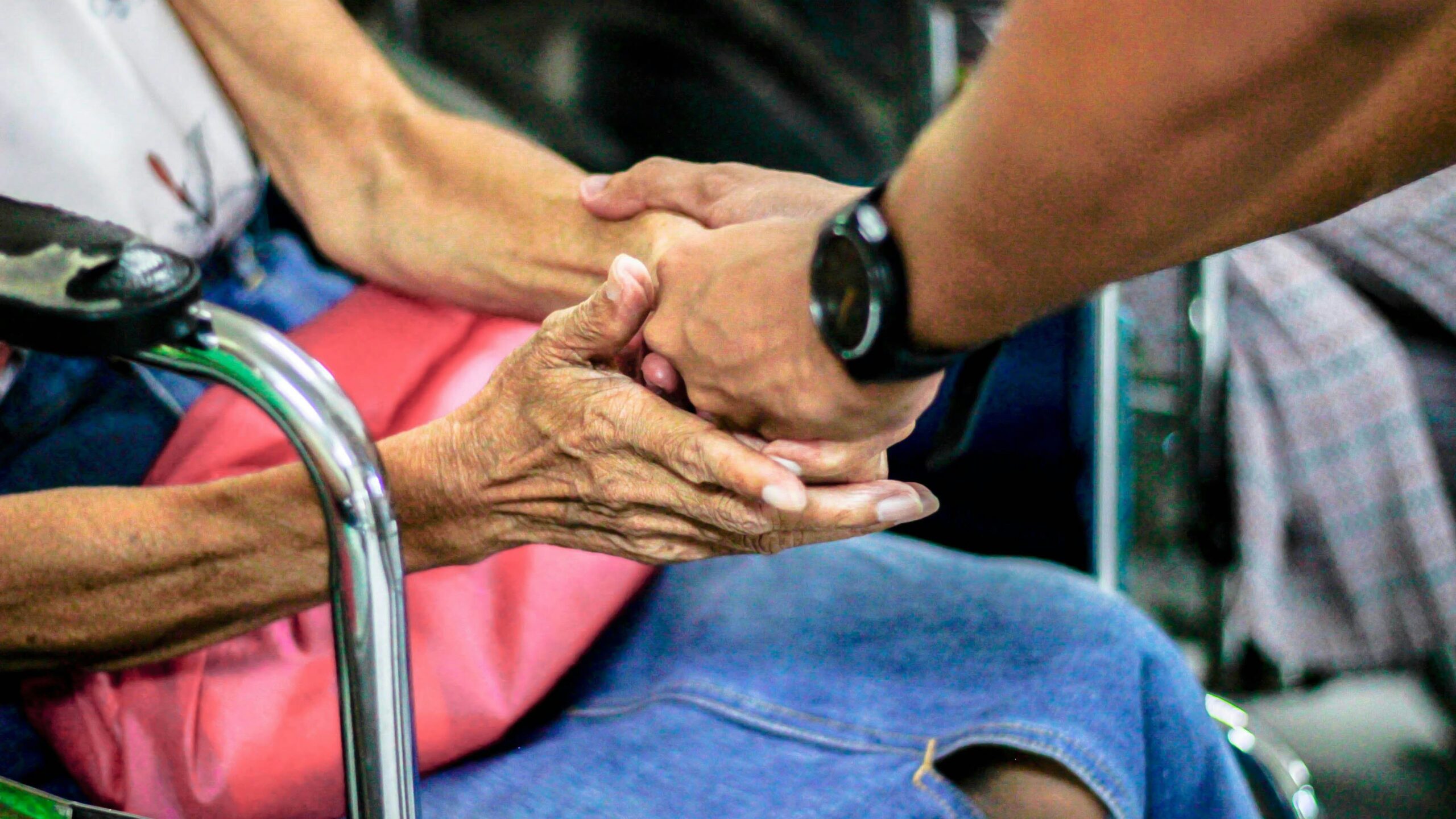 Man holding the hands of a woman in a wheelchair
