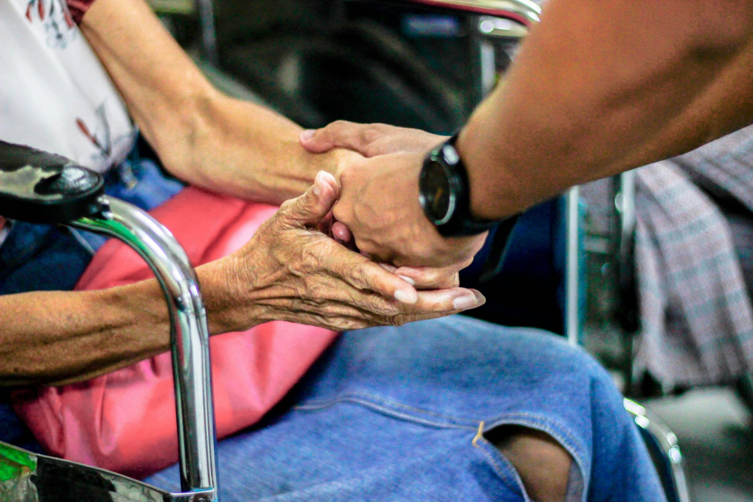 Man holding the hands of a woman in a wheelchair