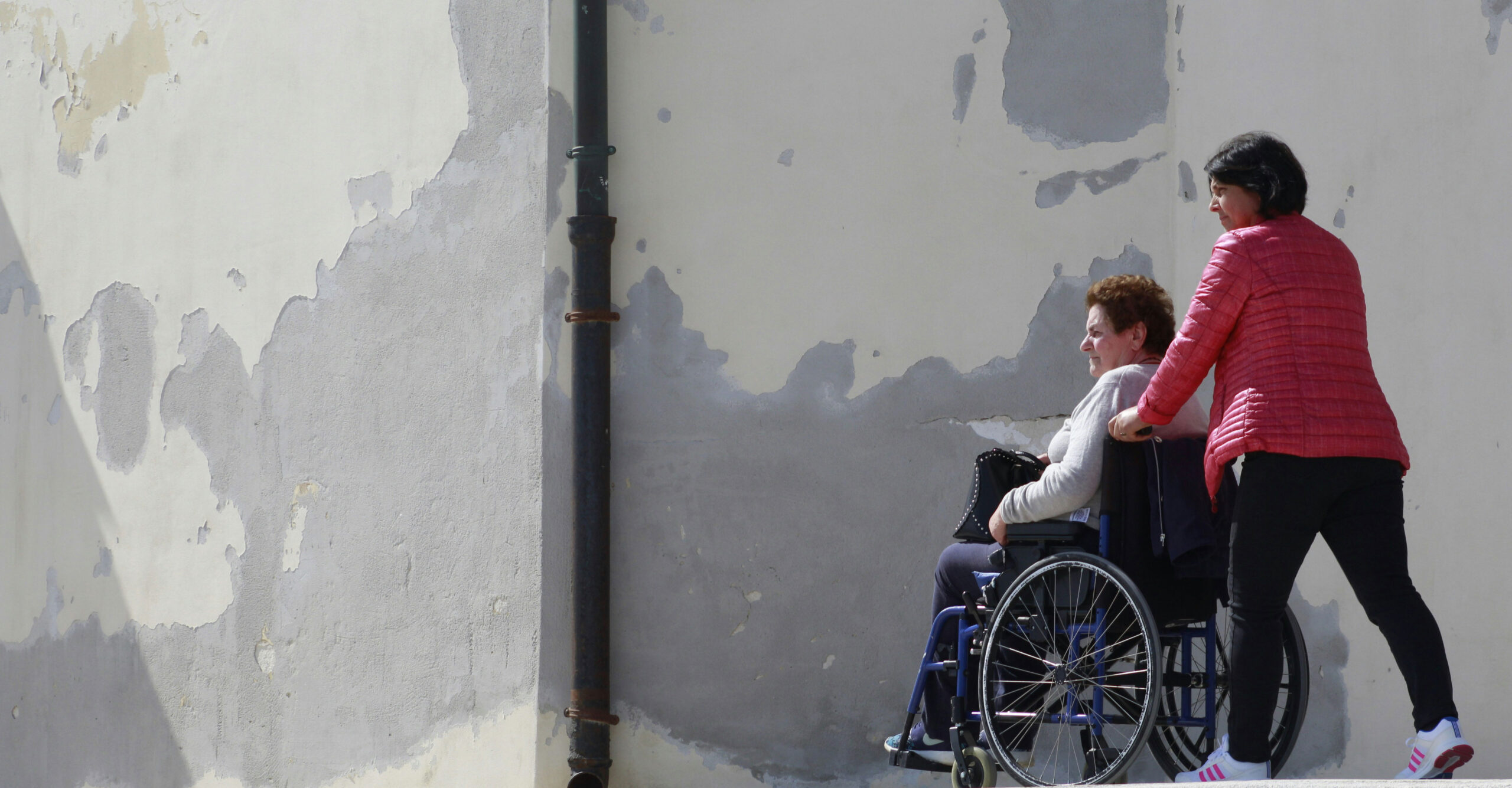 Woman pushing a woman in a wheelchair