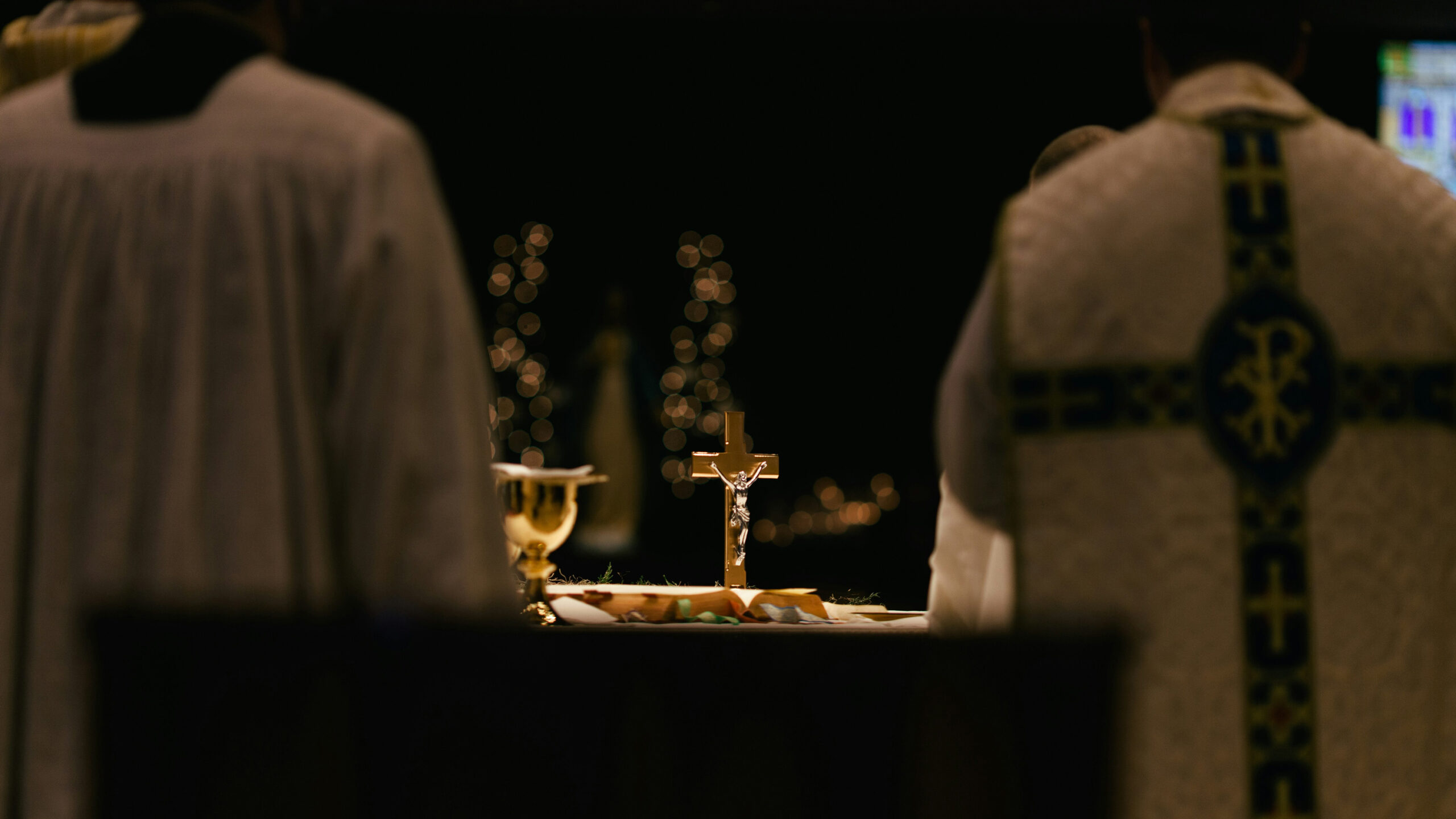 A clear view of the Eucharist in a monstrance between two priests facing toward it