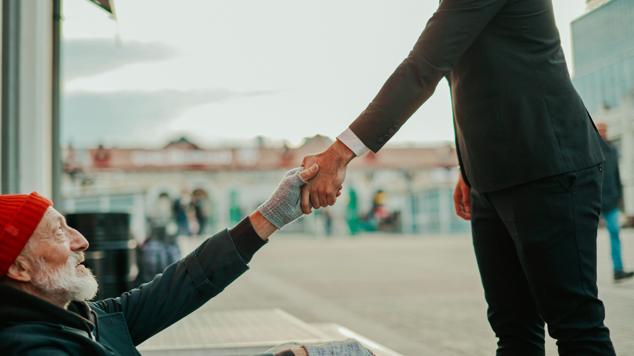 man reaching out to shake the hand of another man