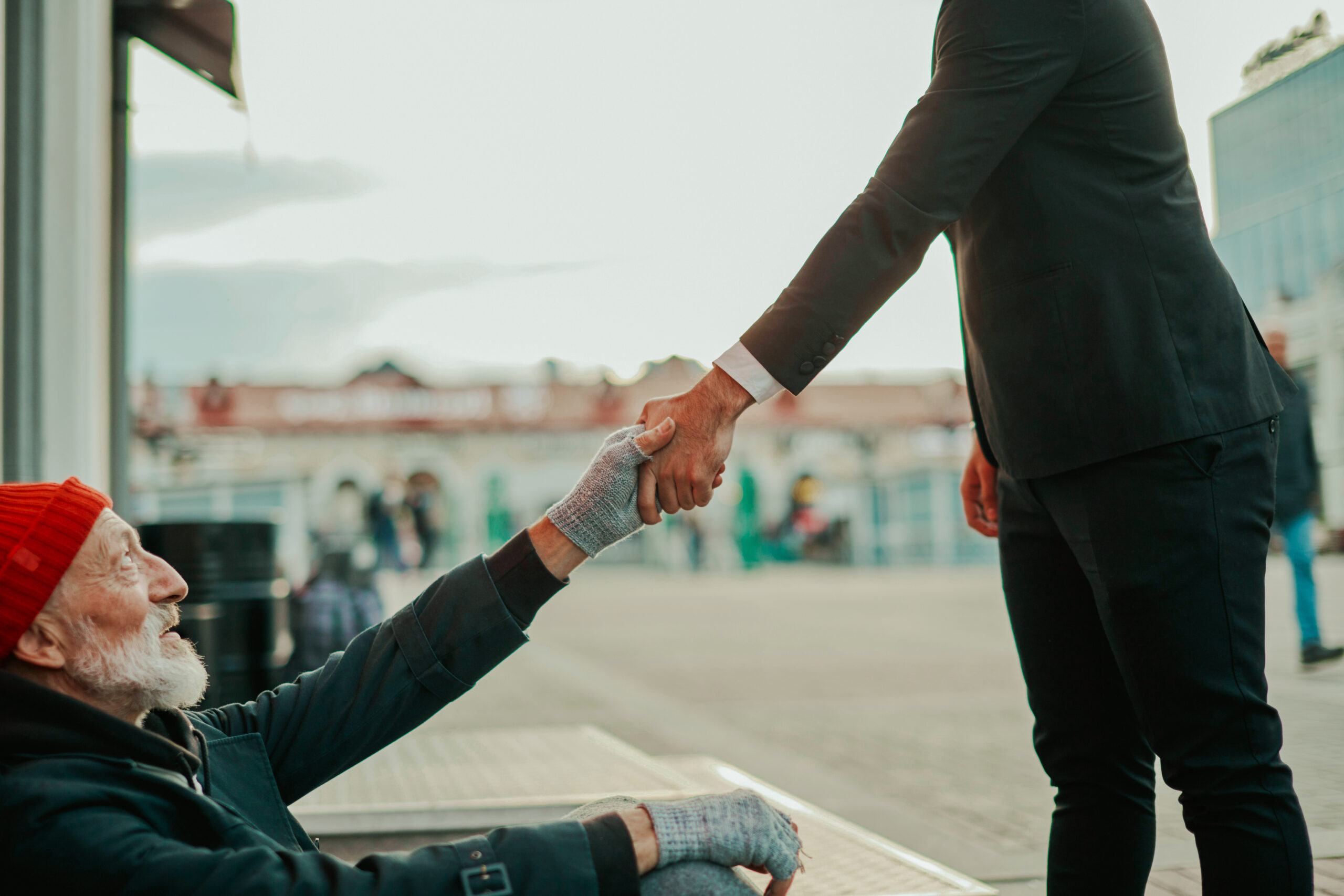 man reaching out to shake the hand of another man