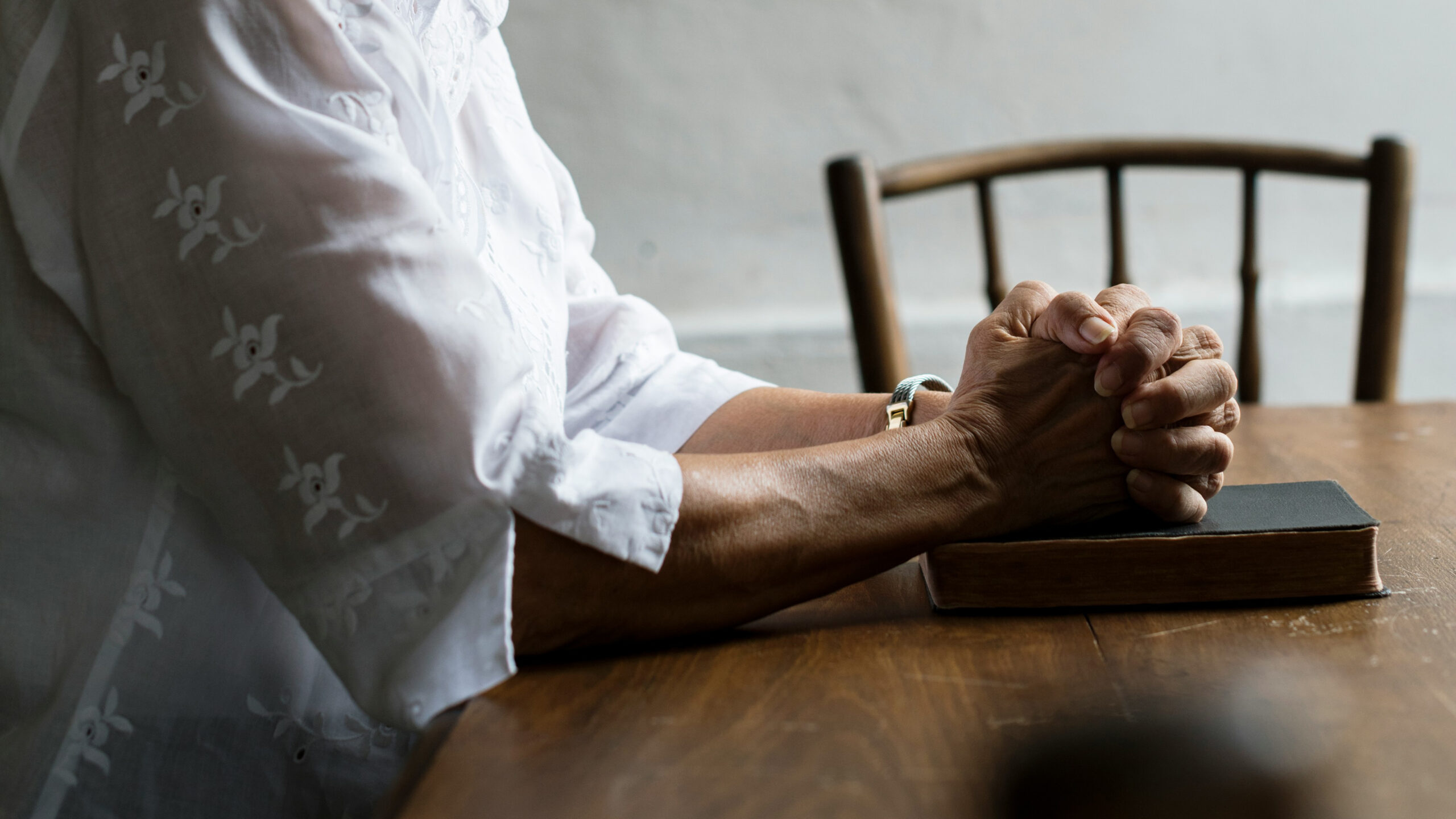 hands folded in prayer over a Bible