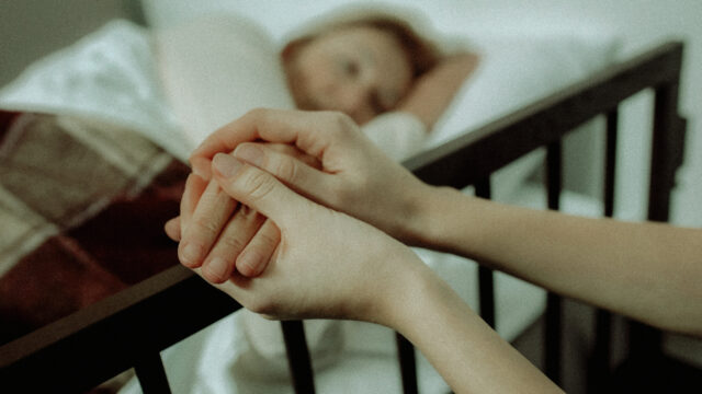 Daughter supporting her terminally ill mother lying on hospital bed