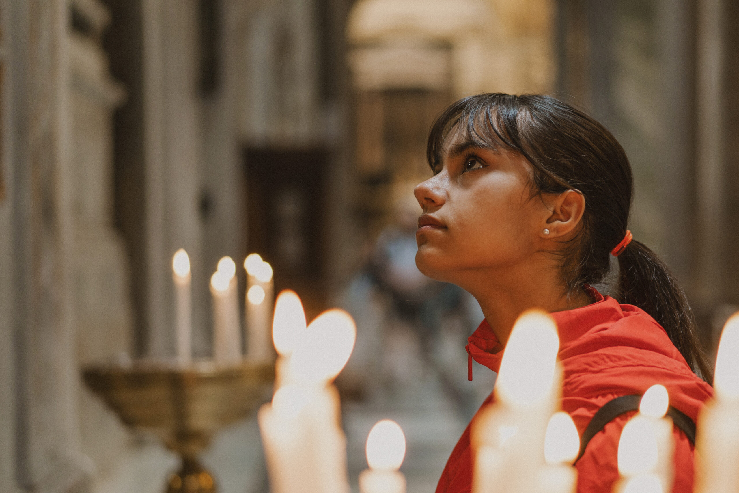 Young girl prayer in a church by candlelight