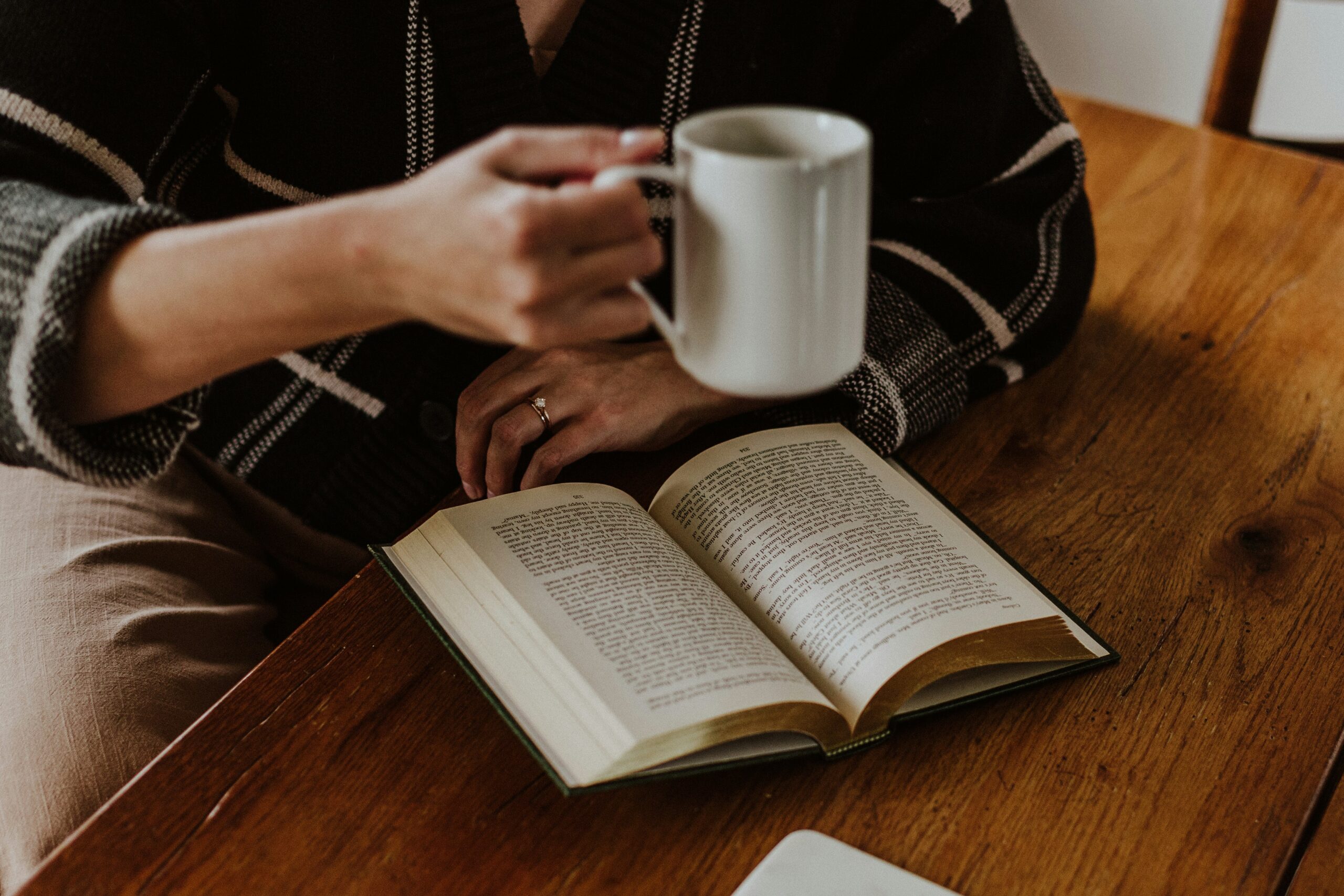 Person sitting and reading a book with coffee