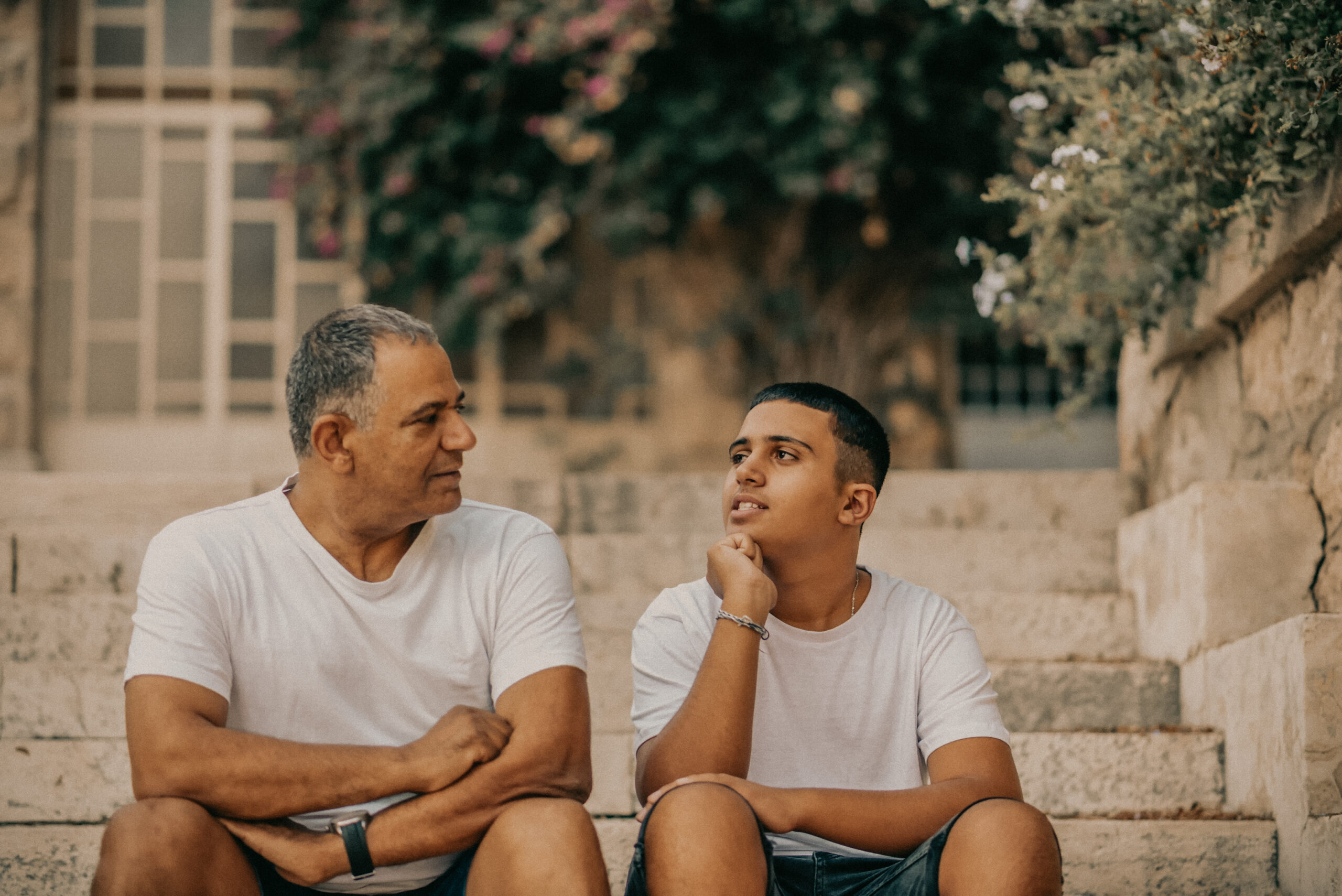 Happy teen young boy rest on stairs speak with father enjoy a talk