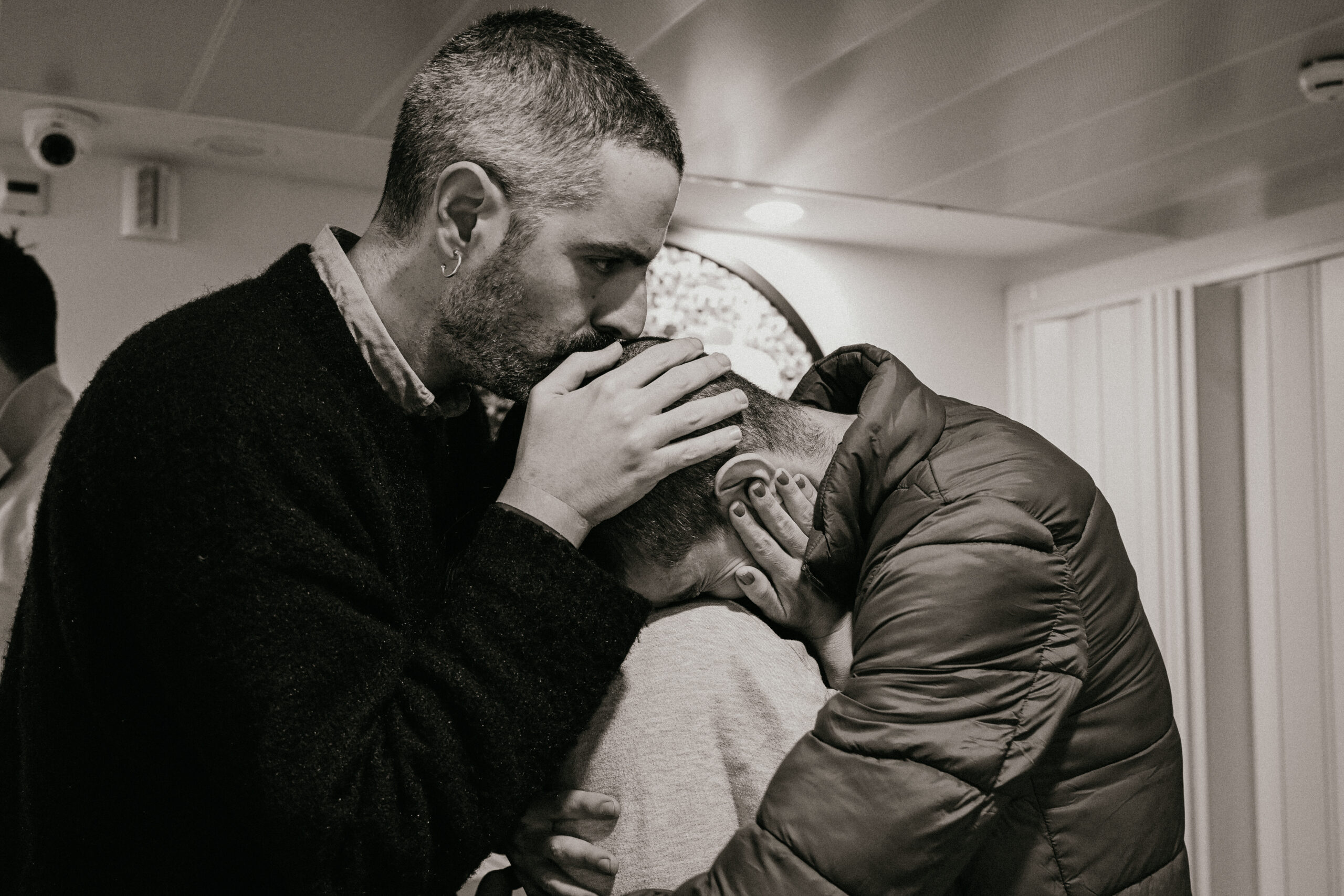 man kissing top of man's head