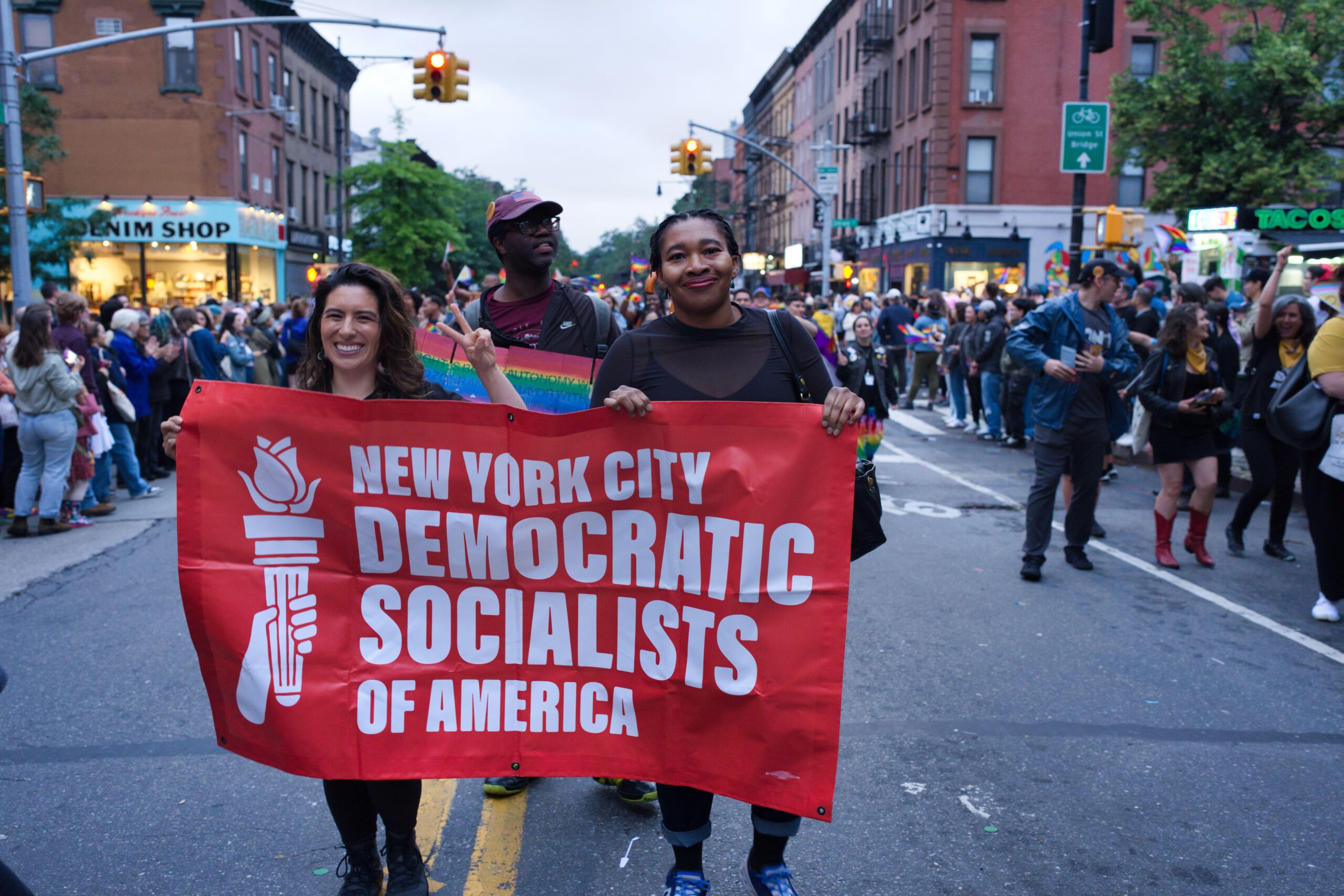 Two women hold a large red banner reading "New York City Democratic Socialists of America"